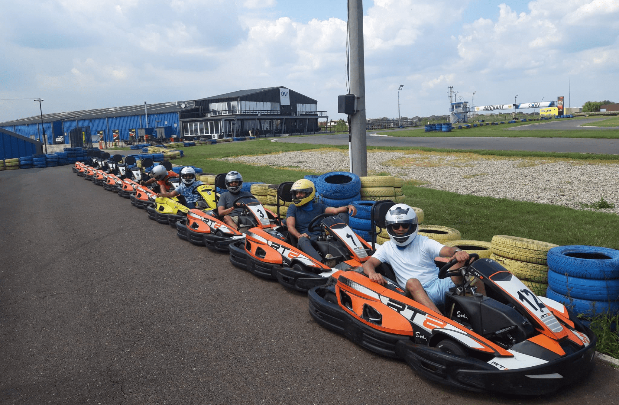Racers in go-karts lined up on a track, ready for a thrilling race at an outdoor karting facility.