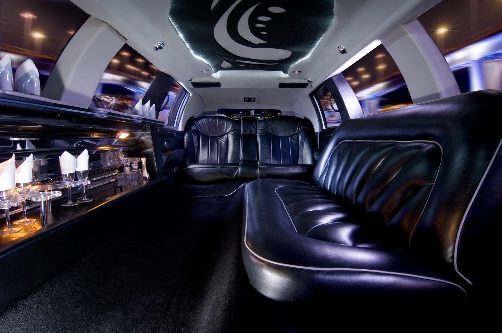 Luxurious black leather interior of a limousine with ambient lighting and glassware, perfect for a stylish night ride.