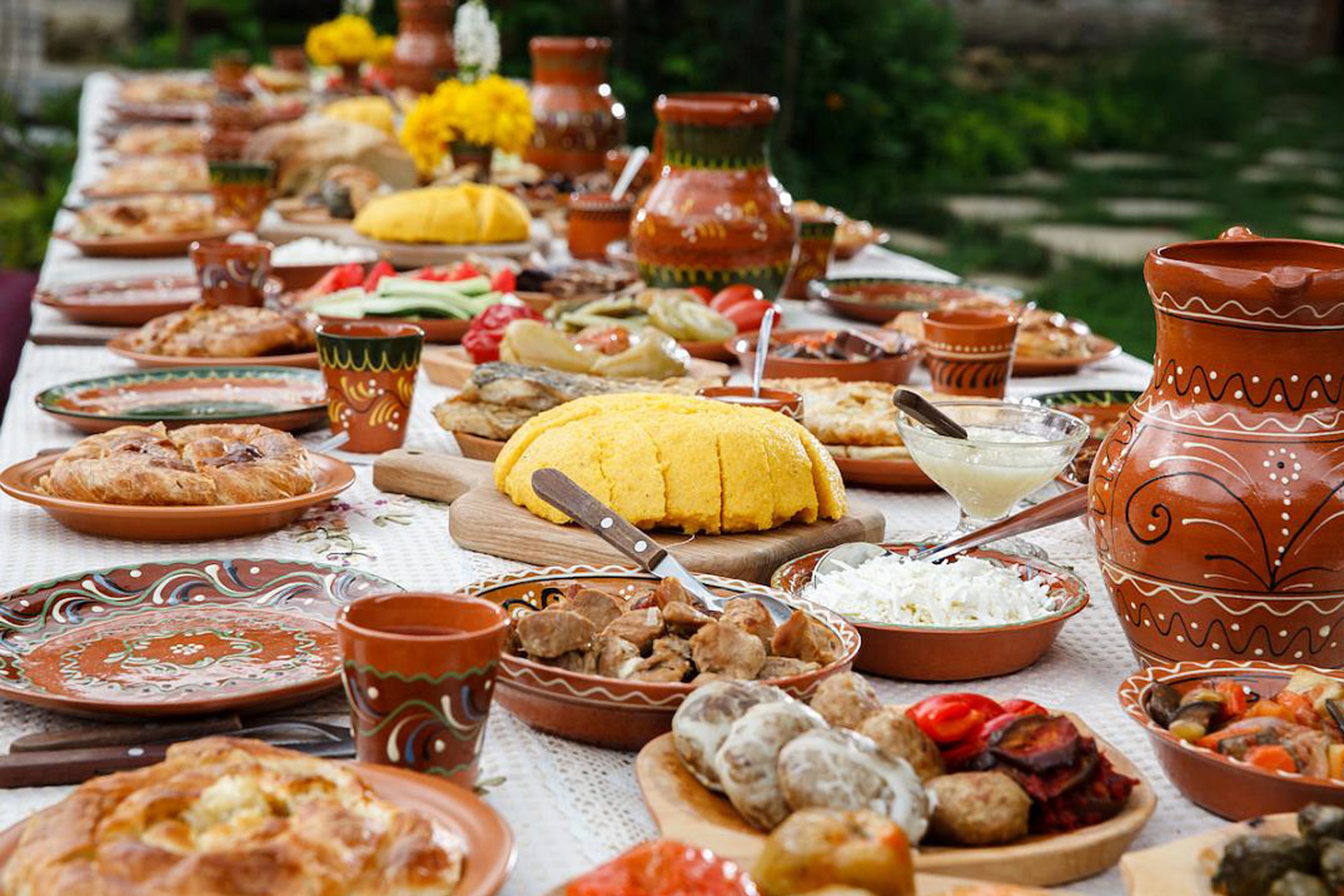 Traditional festive table with diverse dishes, pottery, and vibrant colors, showcasing a rich cultural feast.