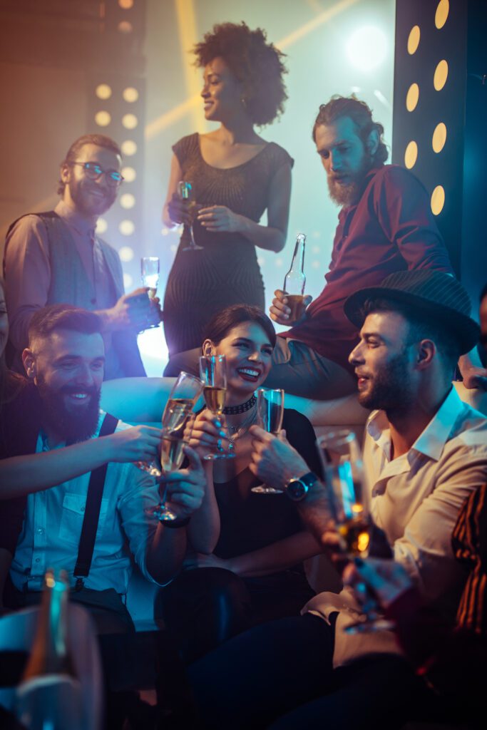 Group of friends enjoying a vibrant party, clinking champagne glasses and smiling together.