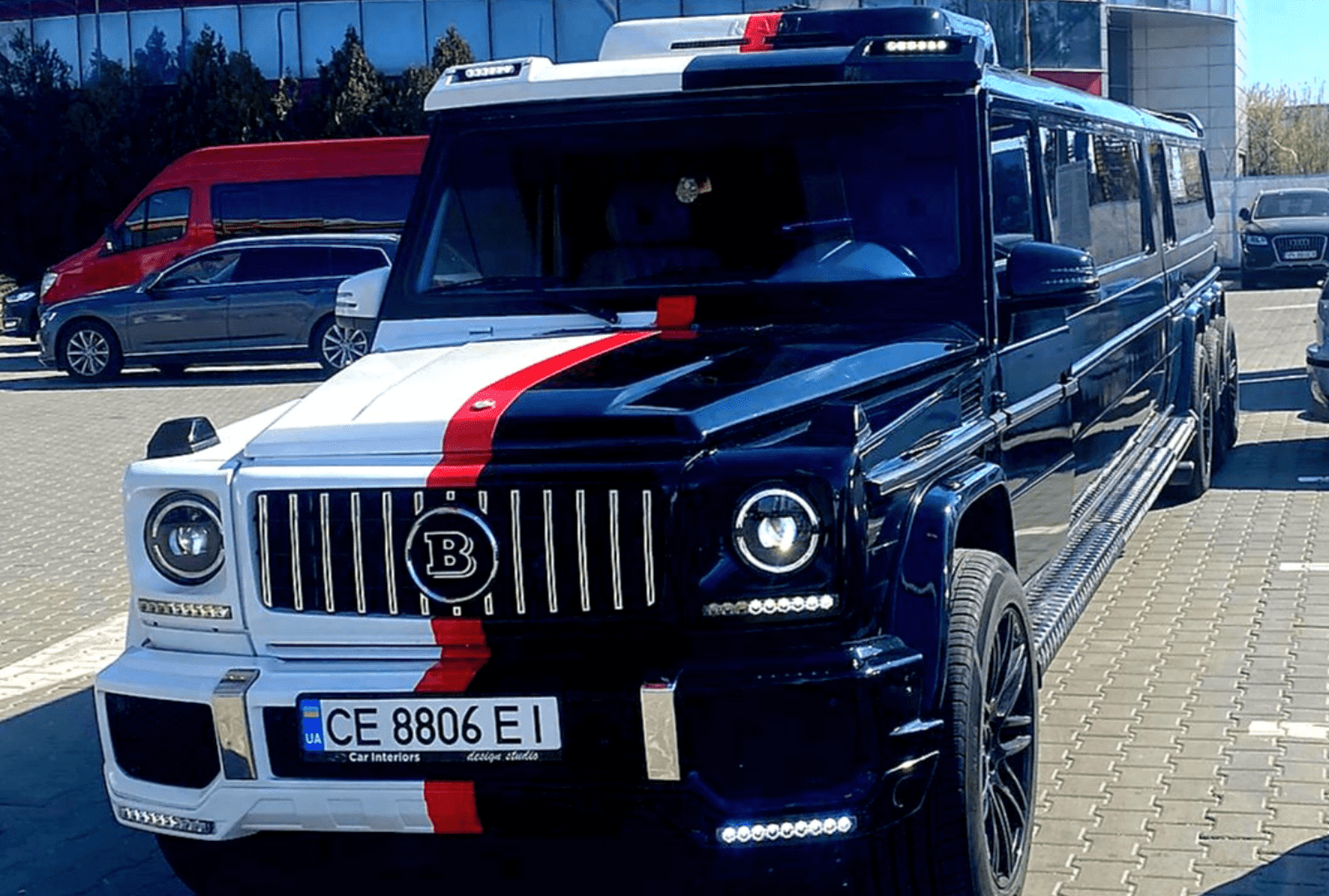Luxurious custom limousine parked, featuring unique black and white design with red stripe accents.