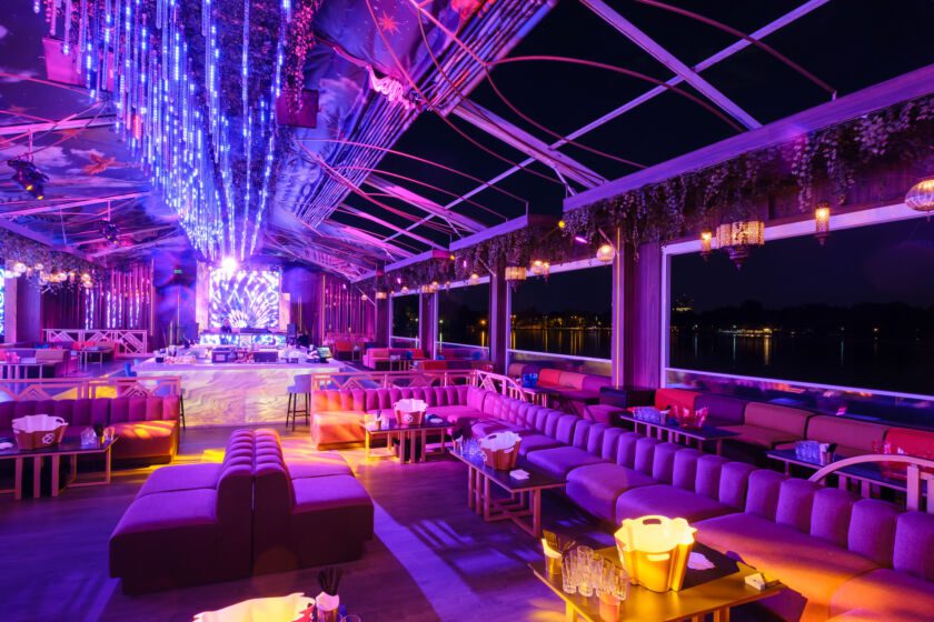 Vibrant rooftop lounge with colorful lighting, modern seating, and city views at night. Ideal for nightlife enthusiasts.
