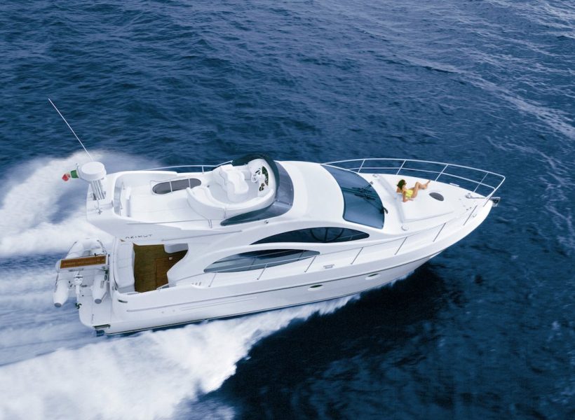 Luxury yacht cruising on blue sea with person relaxing on deck.