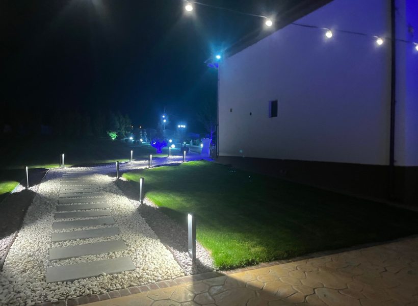 Night garden path with modern lights and landscaped stones, adjacent to a building, creating an inviting atmosphere.