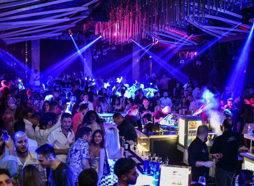 62396023 Crowded nightclub with vibrant lighting and people enjoying the lively atmosphere.