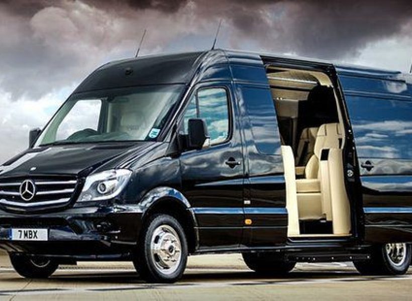 Black luxury Mercedes-Benz Sprinter van with open side door on a cloudy day, showcasing sleek design and spacious interior.