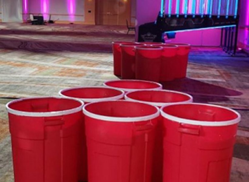 Giant red Solo cups set up for beer pong in a colorful, illuminated room.
