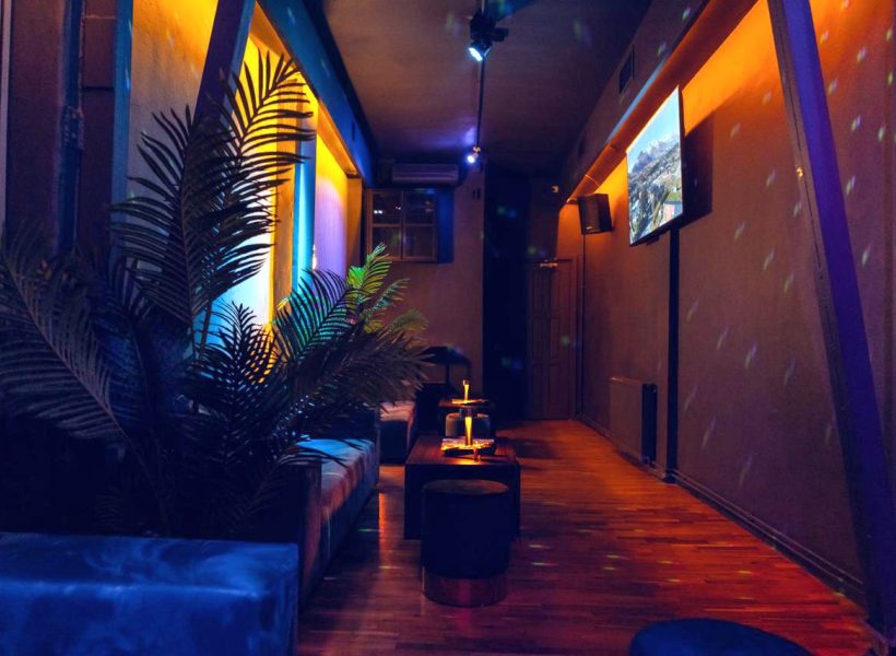 IMG-20250130-WA0013 Dimly lit lounge with cozy seating and vibrant lighting, creating a relaxing atmosphere.