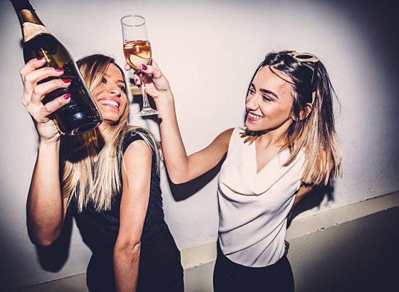 Smiling girls dancing in a nightclub, drinking champagne, having the time of their lives
