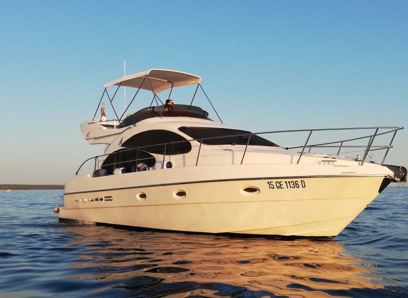 Luxury yacht cruising on calm blue waters under a clear sky.