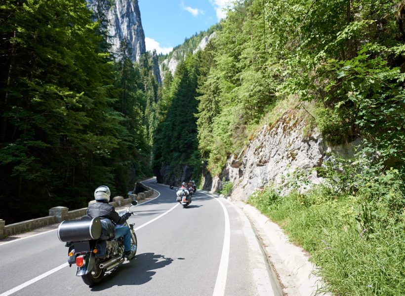 Tourists bikers traveling in motorcycles on mountain road in Bicaz Canyon, Romania between high vertical rocky cliffs. One of the most spectacular roads in Romania. Adventure and travel theme.