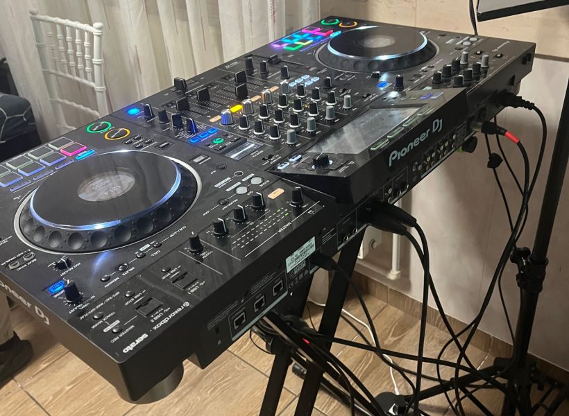 DJ mixing console with colorful controls and turntables ready for a music session, cables visible underneath.