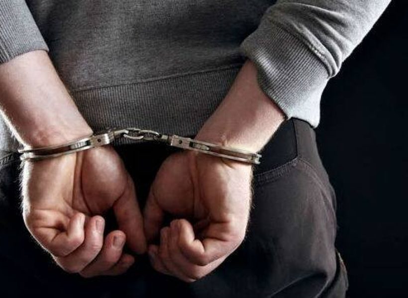 jail-arrested-arrest-prison2 Person in handcuffs facing away, wearing casual clothing, symbolizing arrest or detention against a dark background.