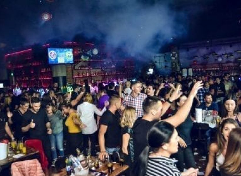 §1 Vibrant nightclub scene with a lively crowd dancing and socializing under colorful lights.